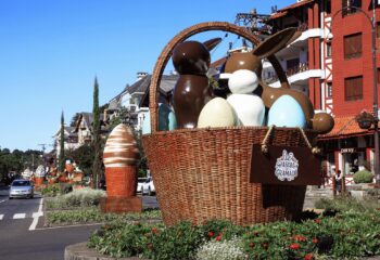 Decoração da Páscoa em Gramado com coelhos de chocolate e ovos coloridos em cestas de vime gigantes, expostas na Avenida das Hortênsias