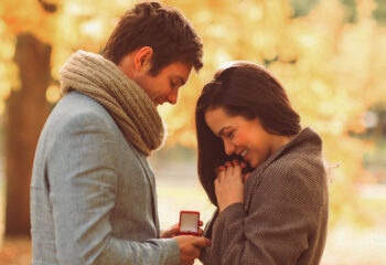 Homem entregando anel de noivado para esposa em um cenário de outono